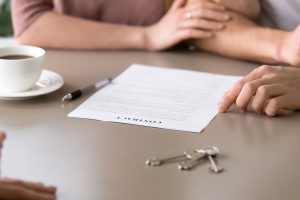 Close up photo of mortgage contract and keys on the table. Couple decided to take out mortgage for buying own apartment, family found reliable building company and purchasing new house