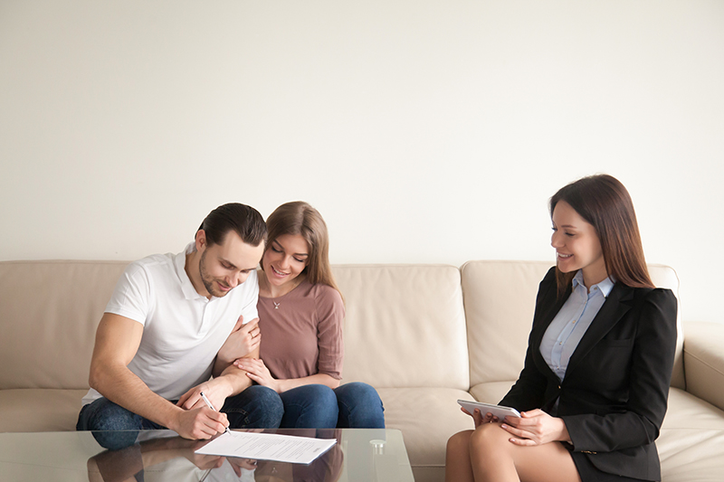 young-man-signing-papers-sitting-wife-buyers-agent