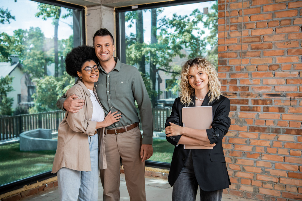 A buyer’s agent in Australia standing next to a cheerful couple after finalising a deal.